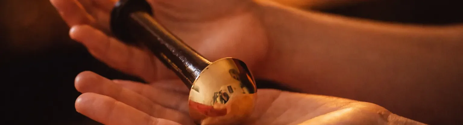 Kansa Wand en bronze tenu dans les mains, outil du massage ayurvédique du visage à Bonsecours
