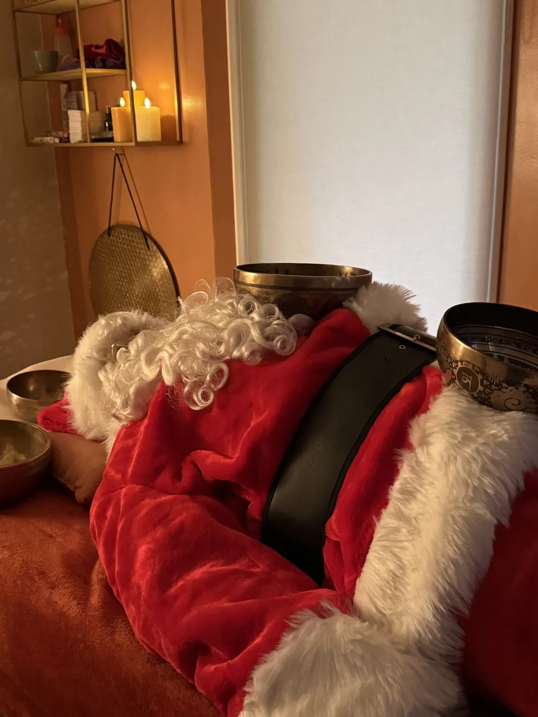 Le Père Noël allongé avec des bols tibétains posés sur lui pendant un massage sonore