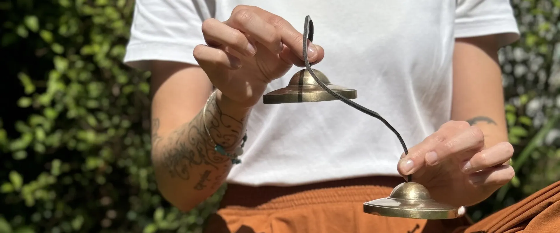 Tingshas tibétaines tenues par leur cordon pendant une méditation en plein air