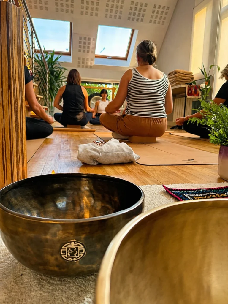 Séance de yoga énergétique en groupe, bols tibétains au premier plan, à Bonsecours